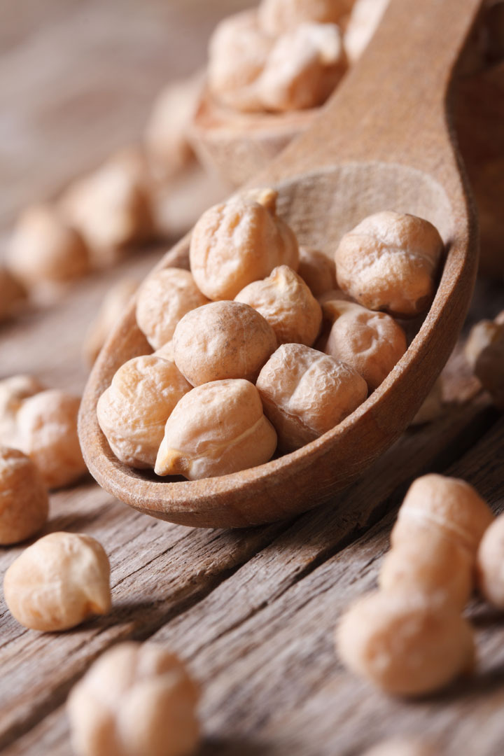dry chick peas on a wood spoon - a main ingredient in Instant Pot Bombay Potatoes