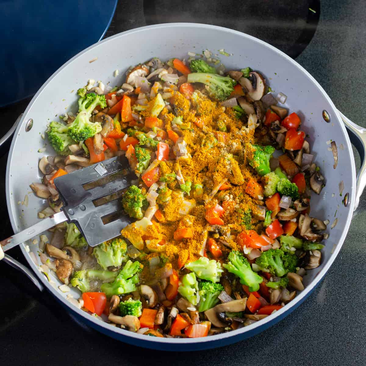 spices added to vegetables in a sauté pan